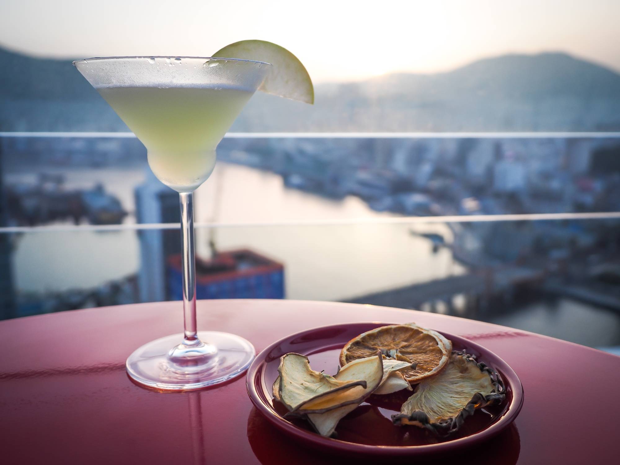 Apple martini with a view of the sun setting over Busan